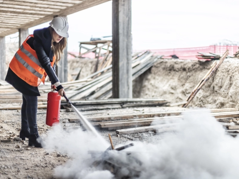 Woman using fire extinguisher on construction site.