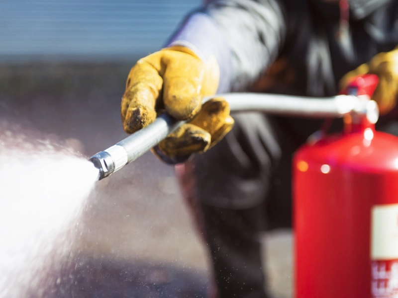 Person using fire extinguisher to put out fire.