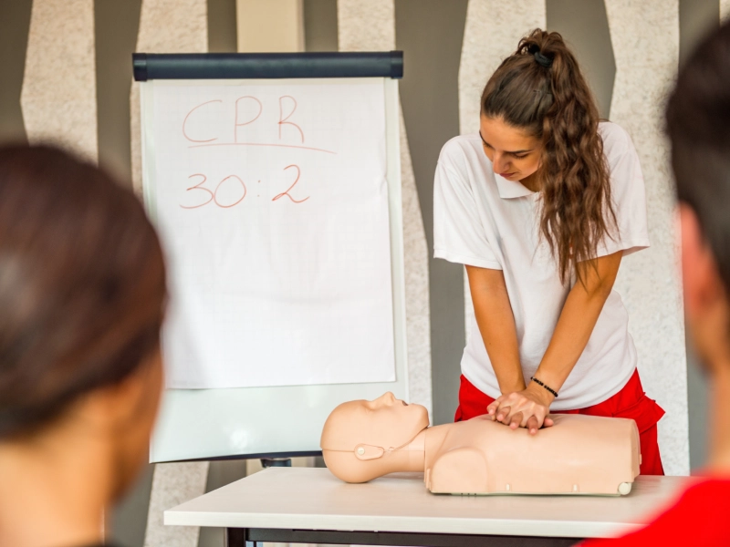 Woman performing CPR on a mannequin.