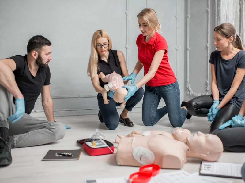 CPR training class with infant and adult dummies.