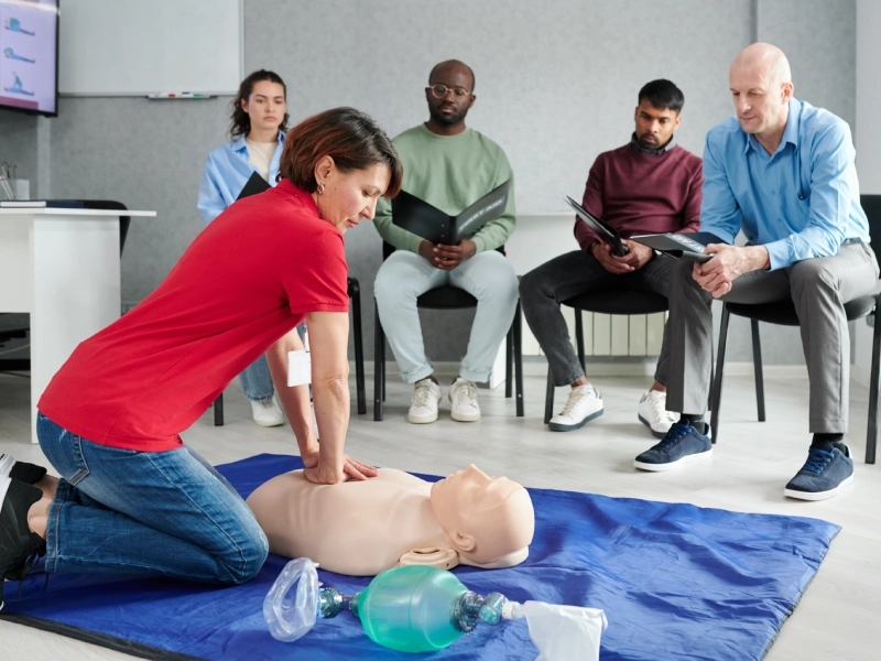 Woman performing CPR on dummy.