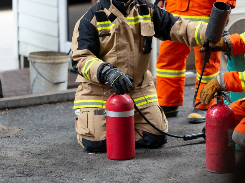 Firefighter kneeling with fire extinguishers.