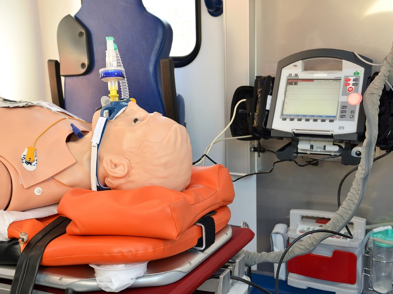 Medical training mannequin on ambulance stretcher.