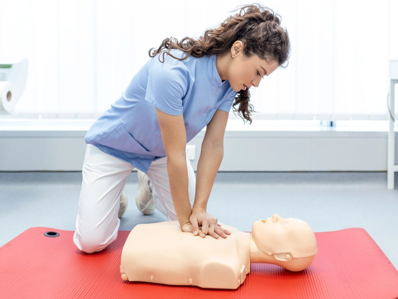 Woman performing CPR on a dummy.