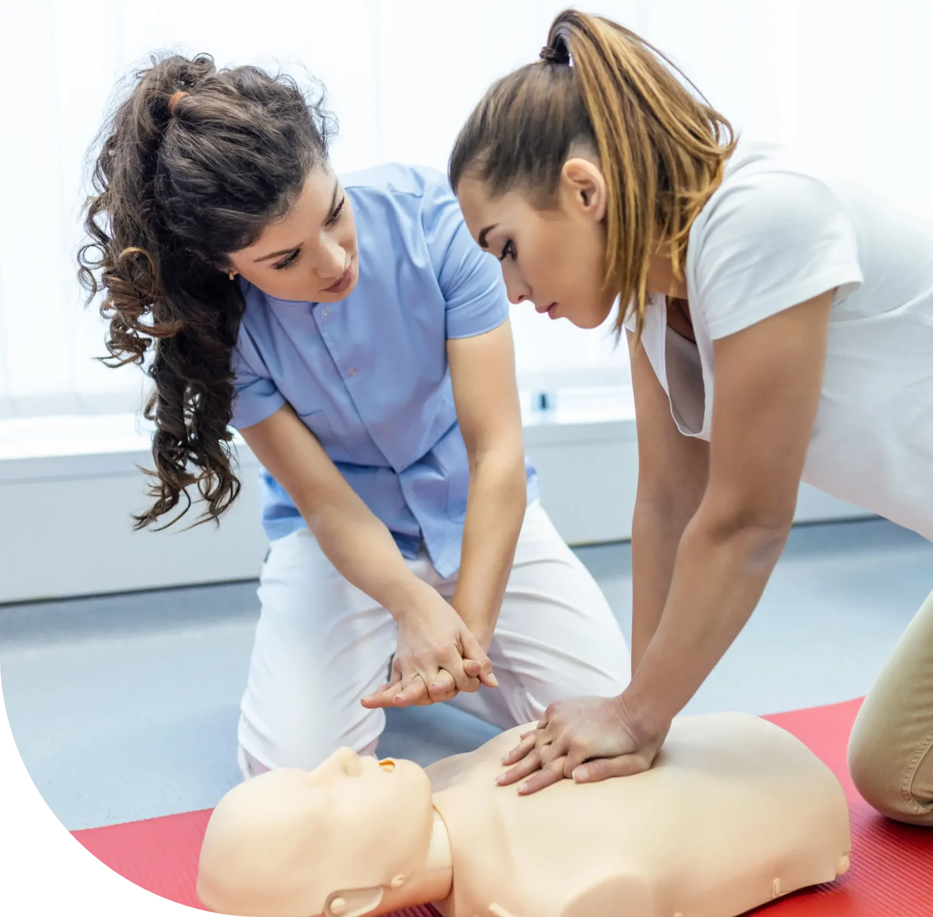 CPR training: two women practicing on a dummy.